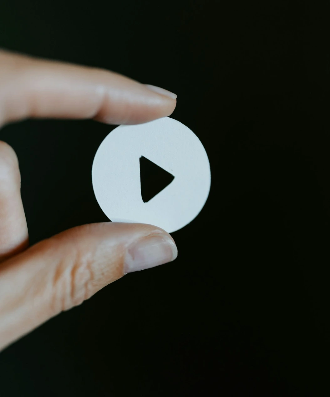 Hand holding a play button icon representing a short video